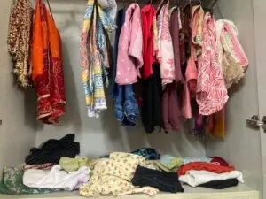 Overstuffed closet filled with clothes on hangers and shelves, symbolizing clutter and excess before embracing the simple life.