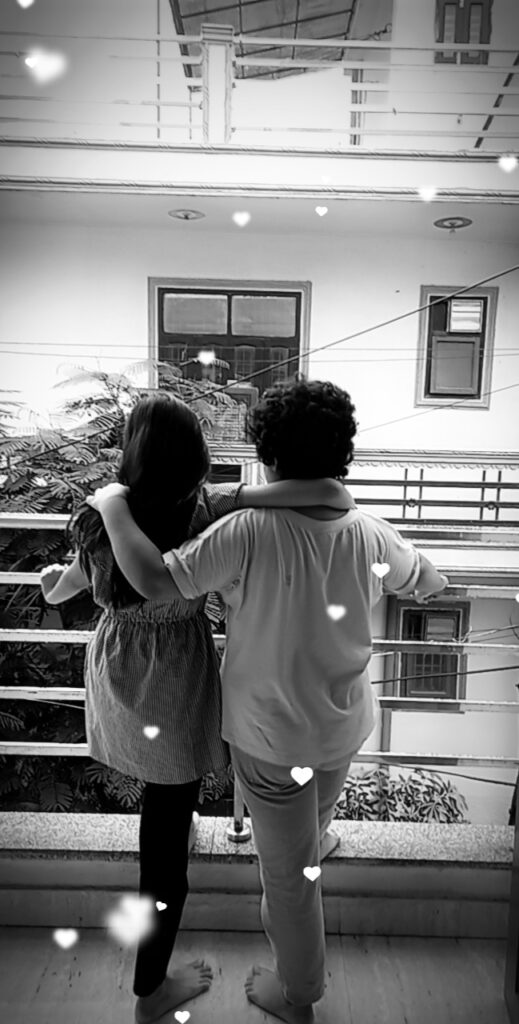 Two friends standing on a balcony, one gently placing a hand on the other's shoulder, showing care, comfort, and emotional support.
