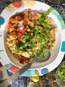 Adding boiled white matar and spices into a bowl to prepare homemade matar kulcha masala