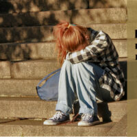 A young girl sitting alone on stairs with her head resting in her lap, with the words "I am not broken. I am not sad. I am not difficult. I am just an introvert — and that is enough."
