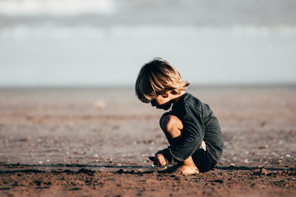 A happy introverted child playing alone near the beach and enjoying her own company in peace and solitude.