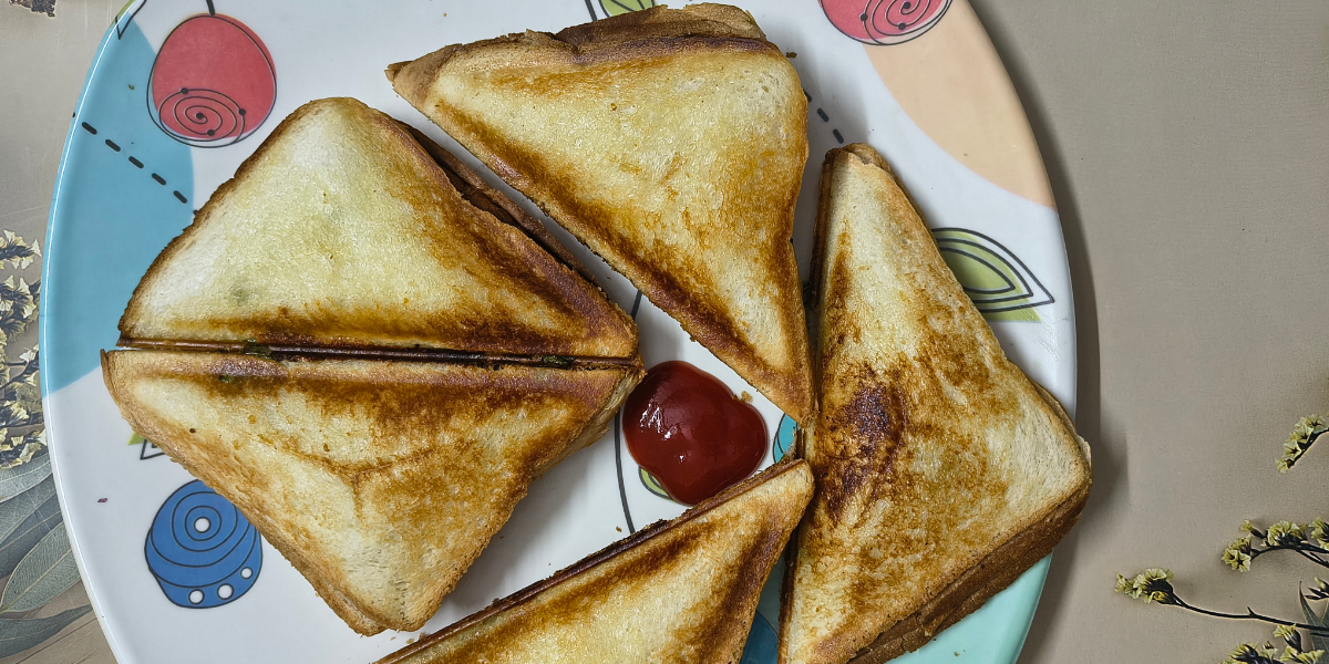 Bell pepper sandwich with corn and cheese filling, toasted until golden brown and served with ketchup on a plate.