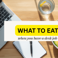 A minimalist wooden office desk with a laptop, a healthy meal bowl, and a glass of water, representing healthy eating habits for a desk job.